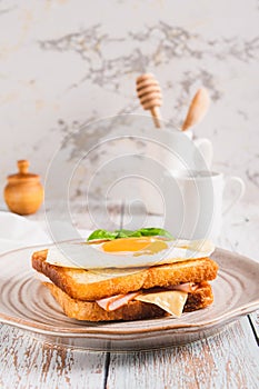 Croque madame sandwich with ham, cheese and egg on a plate on the table vertical view