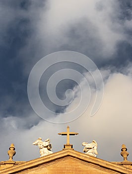 Cross and angel statues on Pamplona Cathedral filtered. Exterior of  Cathedral of Santa Maria la Real on scenic sky background.