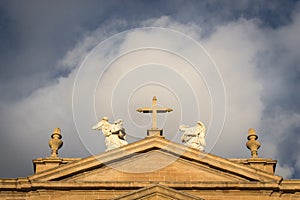 Cross and angel statues on Pamplona Cathedral filtered. Exterior of  Cathedral of Santa Maria la Real on scenic sky background.