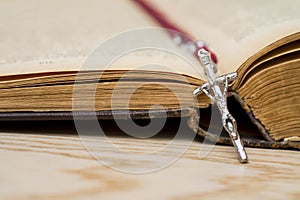 Cross on the Bible on a wooden background. Holy book