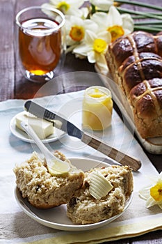 Cross buns served with butter, honey and tea. Easter breakfast.