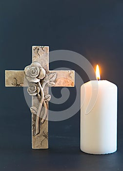 Cross and burning candle against balck background