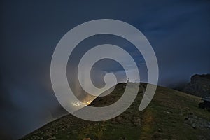 The Cross of Caraiman reflected on the clouds in the night time under the moonlight from Bucegi