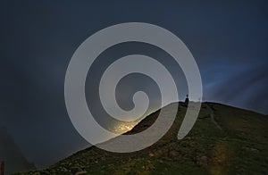 The Cross of Caraiman reflected on the clouds in the night time under the moonlight from Bucegi