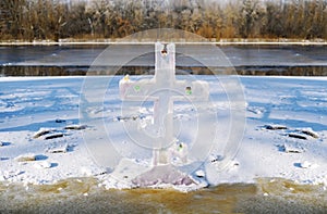Cross christian symbol made from a block of ice on top of the ice on the frozen lake