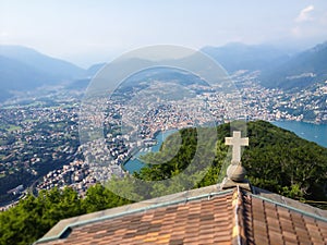 Cross on church rooftop and Top View of Lugano Lake and city from top of Monte San Salvatore with mountain panoramic landscape