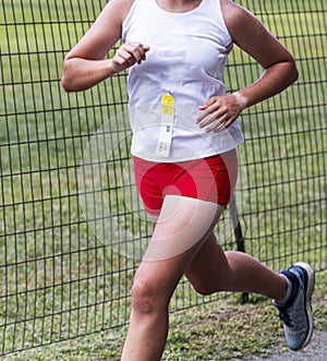 Cross country runner racing next to a wire fence