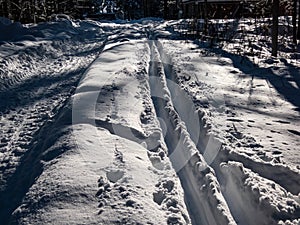 A cross-country ski track forms direct trail that disappears into the distance. The parallel lines of the groomed path, deeply