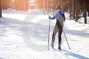 Cross country skiing, happy man winter sport on snowy track, sunset background