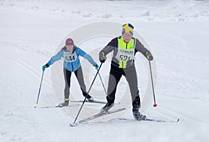 Cross country skiing man wearing swedish hat and woman skiing up