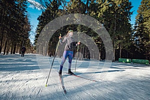 Cross-country skiing woman doing classic nordic cross country skiing in trail tracks in snow covered forest