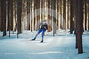 Cross-country skiing woman doing classic nordic cross country skiing in trail tracks in snow covered forest