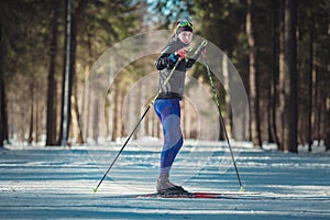 Cross-country skiing woman doing classic nordic cross country skiing in trail tracks in snow covered forest