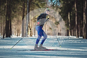 Cross-country skiing woman doing classic nordic cross country skiing in trail tracks in snow covered forest