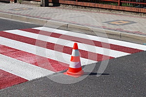 The cross-decorated pedestrian crossing with the still not dried out red. Restriction of traffic by road signs. Update road pedest