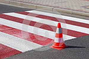 The cross-decorated pedestrian crossing with the still not dried out red. Restriction of traffic by road signs. Update road pedest