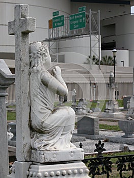 Cross and Funerary Statue and Cemetery with Interstate Roadsigns in the Background