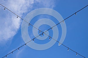 Cross garland wire against blue sky