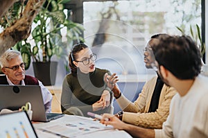 Cross generational colleagues discuss business growth, marketing strategies, and profitability in a meeting.