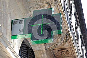 Cross green pharmacy sign outside a pharmacy store in France