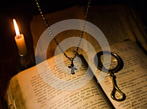 The cross hangs over a prayer book with a magnifying glass
