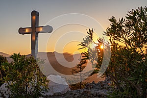 Cross on hill and sunset sky with sunlight