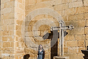 A cross in the historical Torre de Moncorvo Castle in Portugal and a young lady standing next to it photo