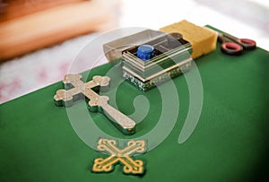 Cross, jars of oil on a table with a green tablecloth in an Orthodox Church