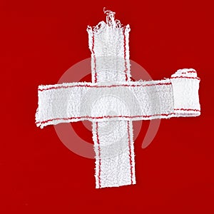 Cross made of white bandages (red background) photo
