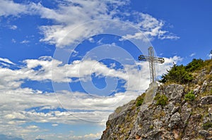 Cross on mountain with cloudy blue sky in background