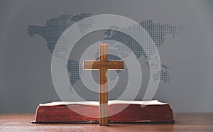 Cross with open Holy Bible on table with world map blur background. mission evangelism and gospel on world. Copy space for text,