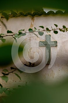 Cross Religion. Symbol. Worship. cross on worn wall among vegetation, plant out of focus and tiles on the top, mexico