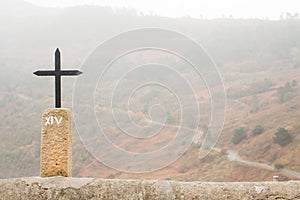 Cross with a road in a forest in the background