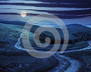 Cross road on hillside meadow in mountain at sunrise at night