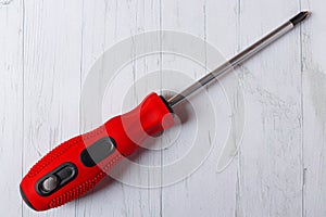 cross screwdriver with red handle on wooden background.