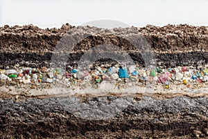 Cross-section of soil layers revealing embedded microplastics and various colored particles illustrating environmental pollution