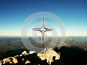 Cross with semi-precious stone raised at mountain summit in Alps. Sharp peak