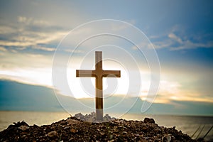 The cross standing on meadow sunset and flare background. Cross on a hill as the morning sun comes up for the day.