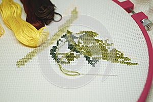 Cross-stitch with colored threads on a white canvas hobby