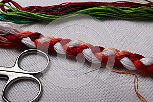 Cross-stitch. Embroidery threads, needle and thread and scissors on the canvas