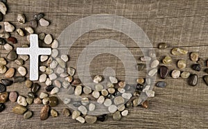 Cross of stones on wooden background for condolence or mourning