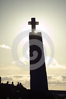 Cross with sun behind it at Cabo da Roca on the Atlantic Ocean in Sintra, Portugal, the westernmost point on the continent of Euro