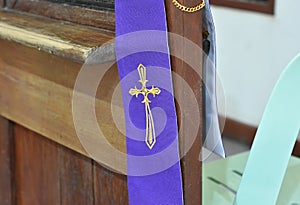 A cross symbol on a purple cloth for the priest is placed on a wooden platform for the confession of sins in Christianity