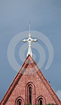 Cross on top of gable of church roof on blue sky background at cathedral of the holy trinity.