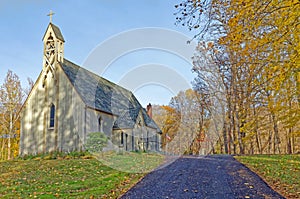 cross on top of historic little country church on top of a hill in Fall