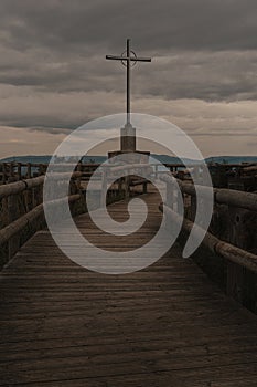 a cross that is on top of a wooden bridge with a dark sky