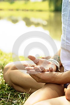 Crossed arms are put on the legs of the girl in meditation. photo