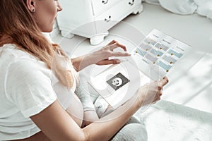 Precious pregnant woman in white t-shirt checking gestational age