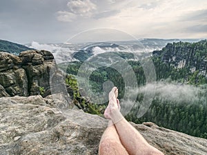 Crossed legs take a rest on mountain trail. Sweaty male legs