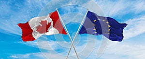 crossed national flags of Canada and The European Union flag waving in the wind at cloudy sky. Symbolizing relationship, dialog,